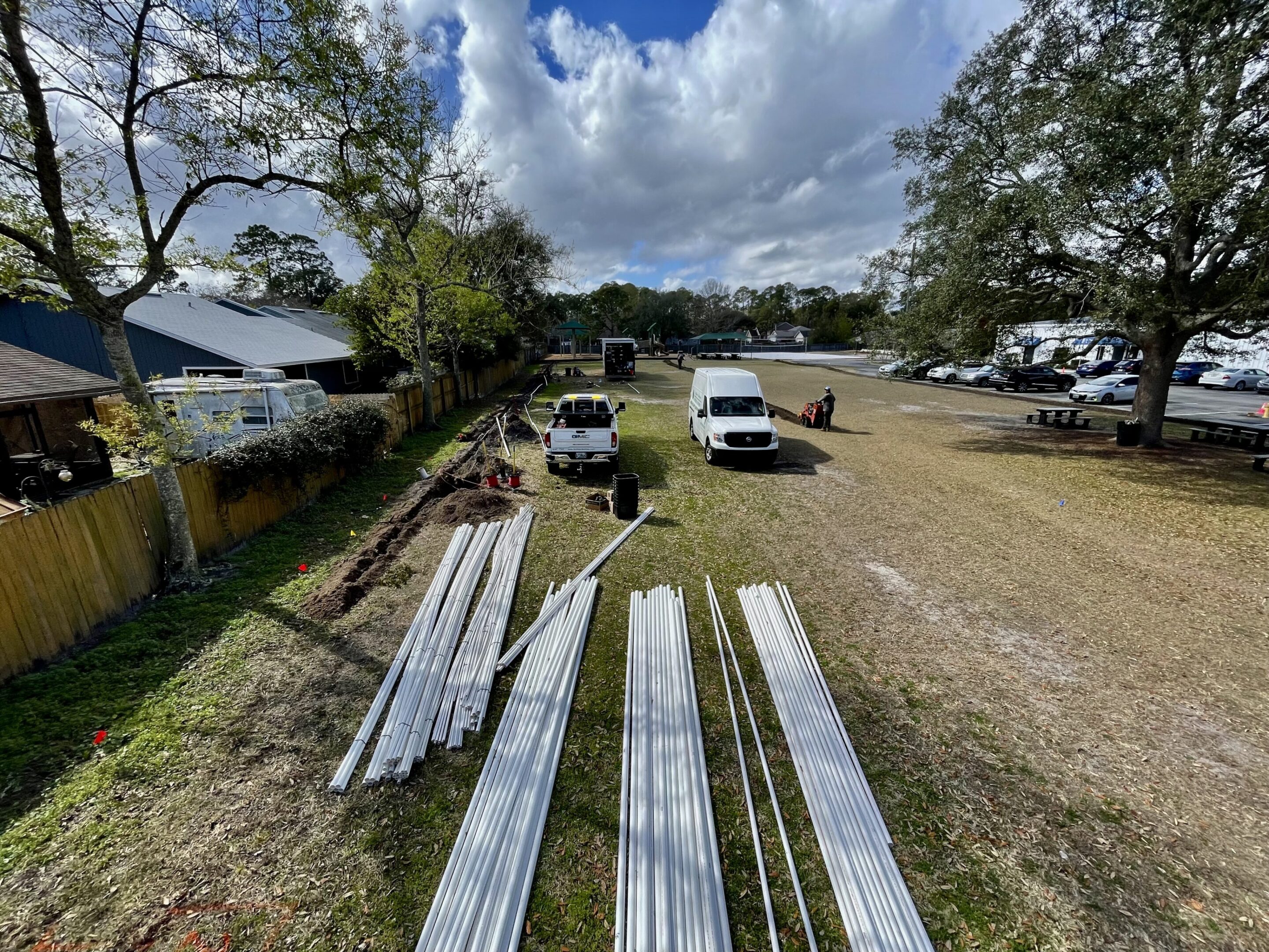 Metal panels laid out on the ground near vehicles under a partly cloudy sky.